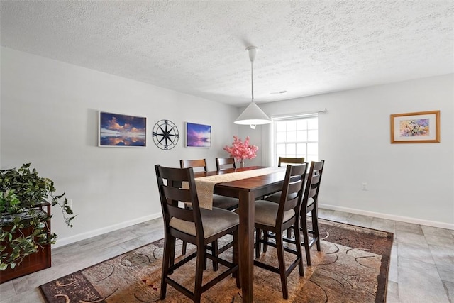 dining room featuring baseboards and a textured ceiling
