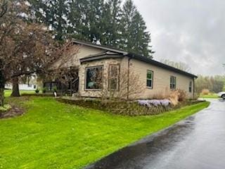 view of side of home featuring a lawn and driveway