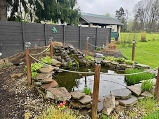 view of yard with fence and a garden pond