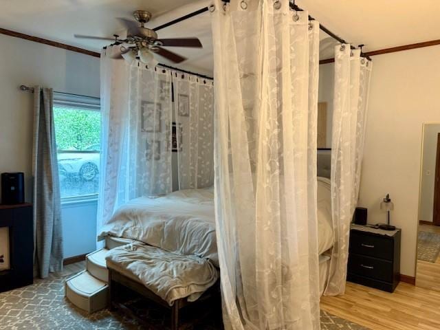 bedroom with crown molding, a ceiling fan, and wood finished floors