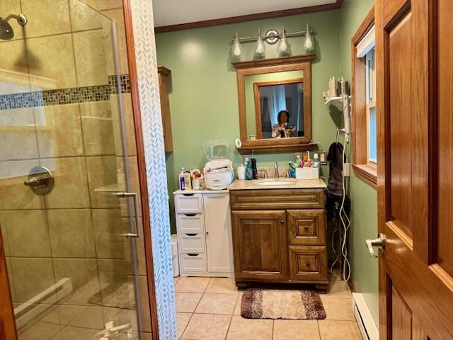 bathroom with crown molding, tile patterned flooring, baseboard heating, a shower stall, and vanity