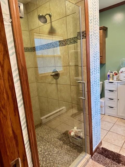 bathroom featuring crown molding, toilet, tile patterned flooring, and a stall shower