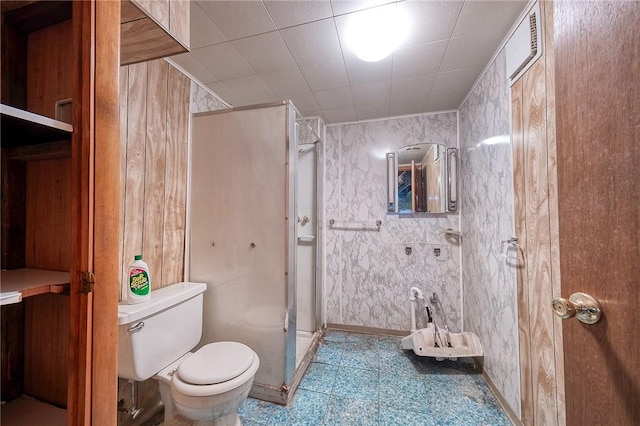 bathroom featuring toilet, baseboards, and a stall shower