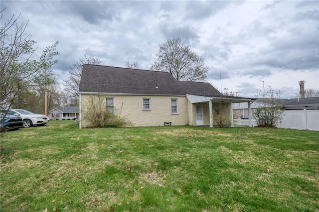 rear view of house featuring a yard and fence