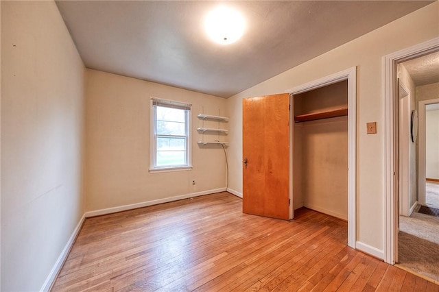 unfurnished bedroom featuring light wood-style floors, baseboards, and a closet
