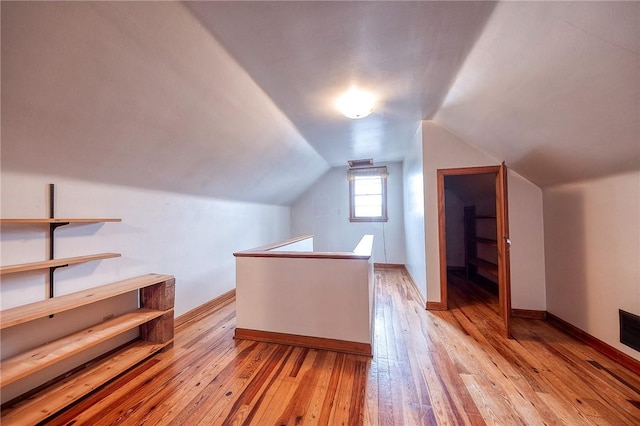 additional living space featuring baseboards, vaulted ceiling, and light wood-type flooring