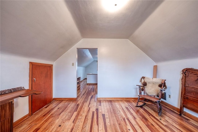 additional living space featuring light wood-style floors, baseboards, and vaulted ceiling