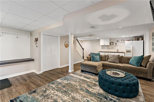 living room featuring baseboards, a paneled ceiling, and wood finished floors