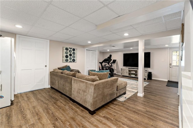 living area featuring baseboards, recessed lighting, wood finished floors, and a paneled ceiling