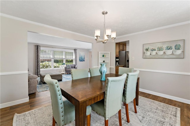 dining space with ornamental molding, wood finished floors, and a chandelier