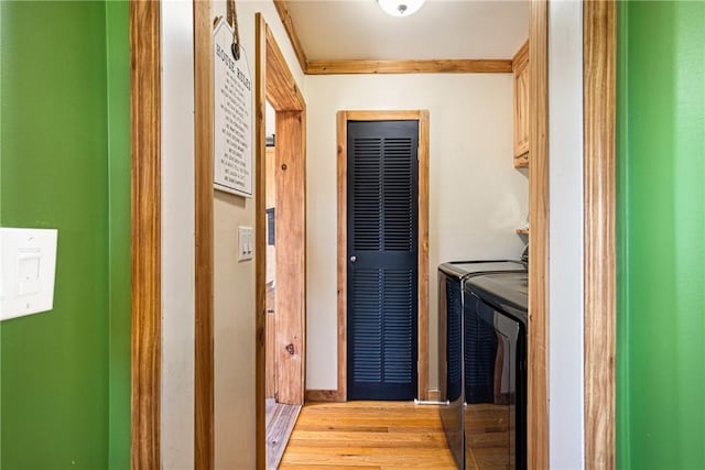 laundry area with a heating unit, washer and dryer, baseboards, cabinet space, and light wood-style flooring