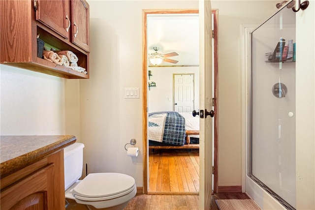 full bathroom featuring vanity, a shower with door, toilet, hardwood / wood-style floors, and ensuite bath