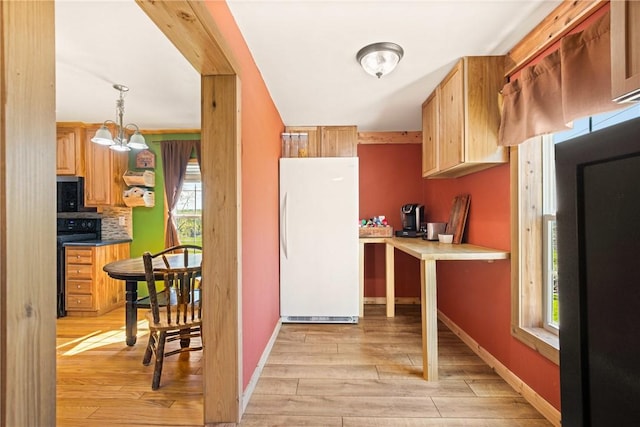 kitchen featuring light wood-style floors, baseboards, a notable chandelier, and black appliances
