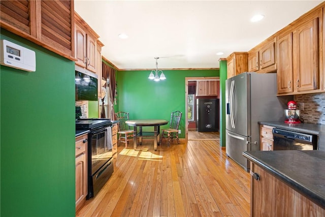 kitchen with pendant lighting, dark countertops, tasteful backsplash, light wood-style flooring, and black appliances