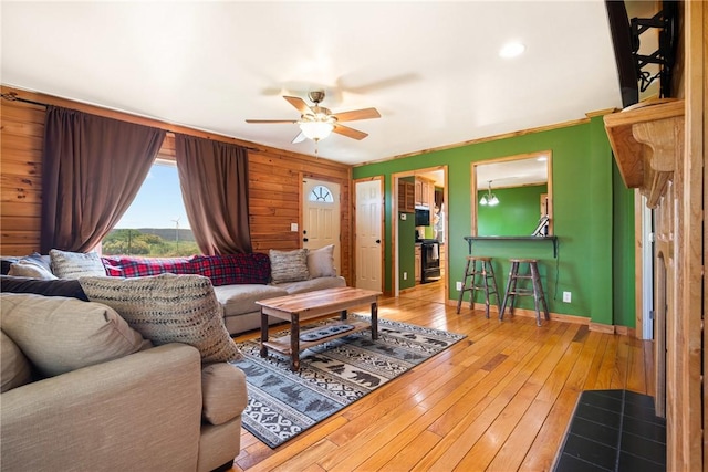 living area with a ceiling fan, wood walls, and hardwood / wood-style floors