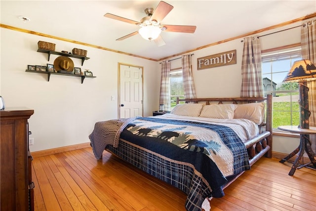 bedroom featuring baseboards, multiple windows, ornamental molding, and light wood finished floors