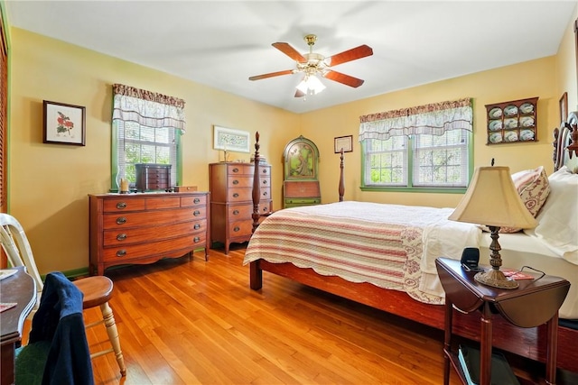 bedroom with multiple windows, a ceiling fan, and wood finished floors