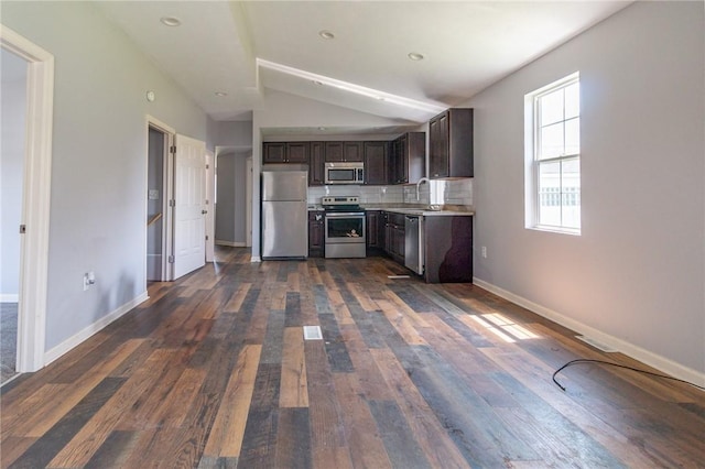 kitchen with dark brown cabinetry, tasteful backsplash, a sink, appliances with stainless steel finishes, and vaulted ceiling
