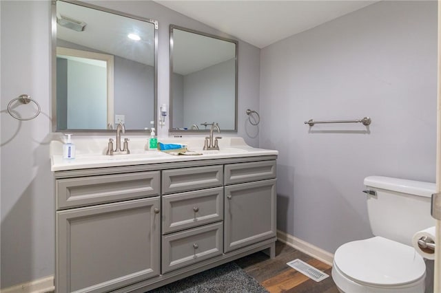 bathroom with visible vents, wood finished floors, toilet, baseboards, and a sink