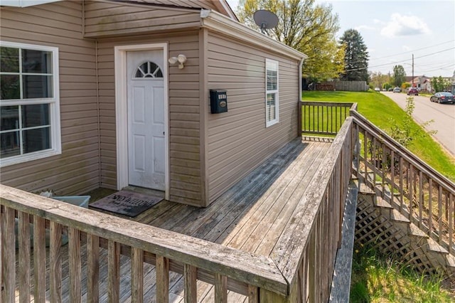 wooden deck featuring a lawn and stairway