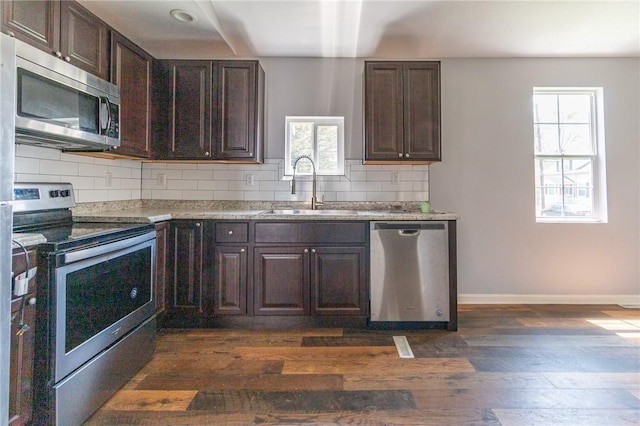 kitchen featuring dark brown cabinetry, appliances with stainless steel finishes, dark wood-style floors, and a sink