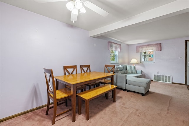 dining area with light carpet, a ceiling fan, beam ceiling, and visible vents