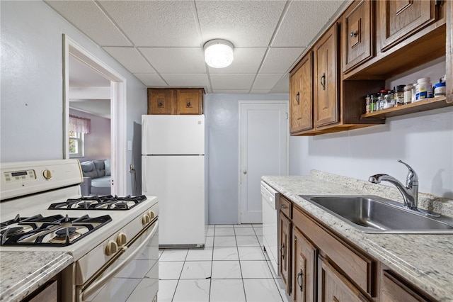 kitchen featuring brown cabinetry, marble finish floor, white appliances, a drop ceiling, and a sink
