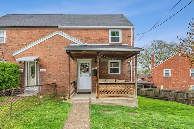view of front of house with brick siding, outdoor lounge area, a fenced backyard, and a front lawn