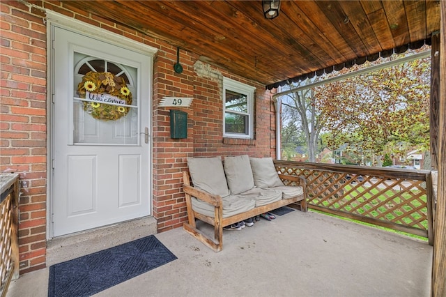 view of exterior entry with covered porch and brick siding