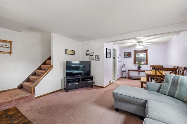 carpeted living area featuring baseboards, ceiling fan, and stairway