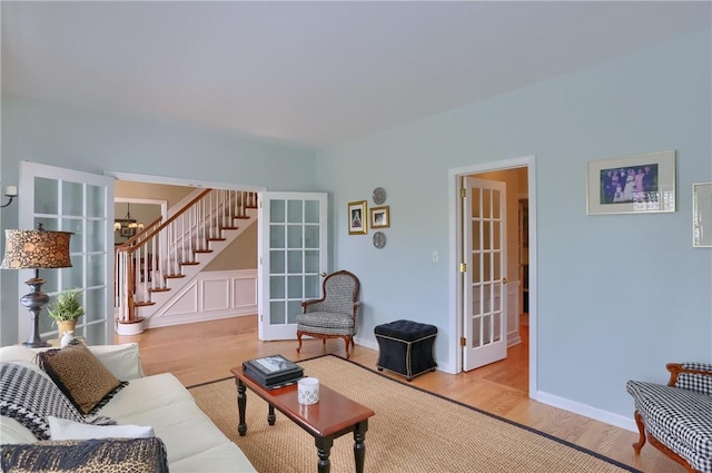 living area with an inviting chandelier, french doors, stairs, and wood finished floors