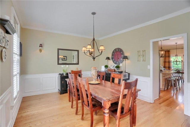 dining room with a wainscoted wall, a decorative wall, light wood-type flooring, and a chandelier