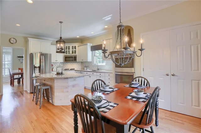 dining space with an inviting chandelier, ornamental molding, recessed lighting, and light wood-type flooring