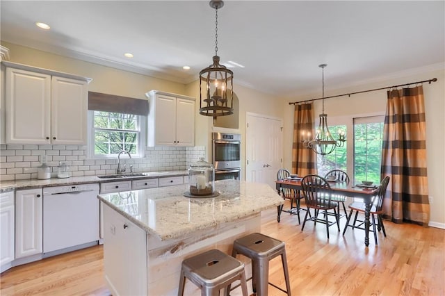 kitchen with a sink, white dishwasher, plenty of natural light, and an inviting chandelier