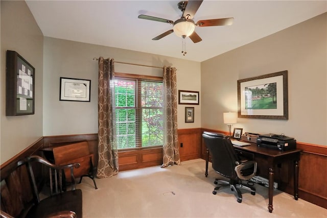 carpeted office with ceiling fan and a wainscoted wall