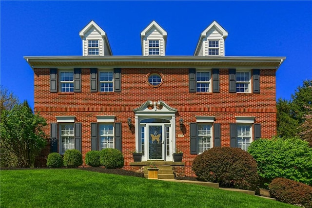 colonial inspired home with brick siding and a front yard