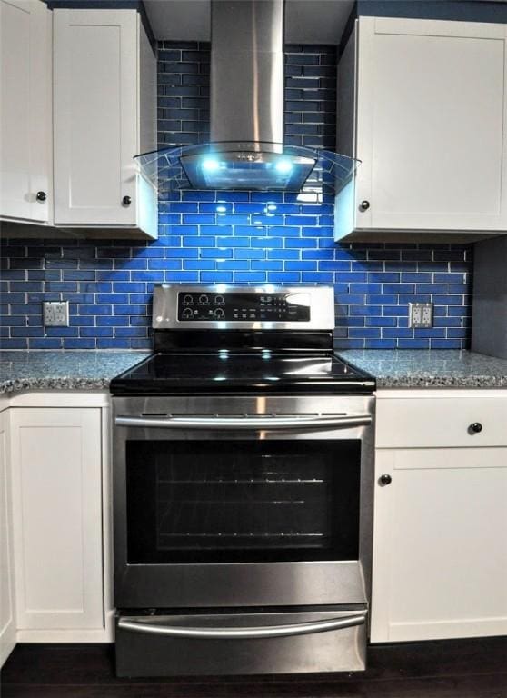 kitchen with white cabinetry, stainless steel electric stove, decorative backsplash, and wall chimney exhaust hood