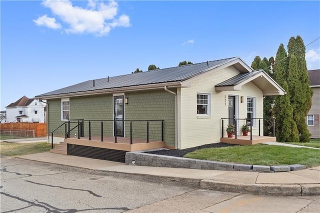 back of house featuring fence, a wooden deck, a yard, and metal roof