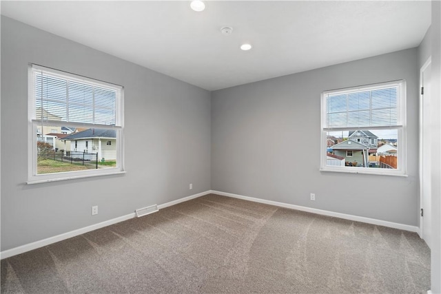 spare room with carpet floors, recessed lighting, baseboards, and visible vents