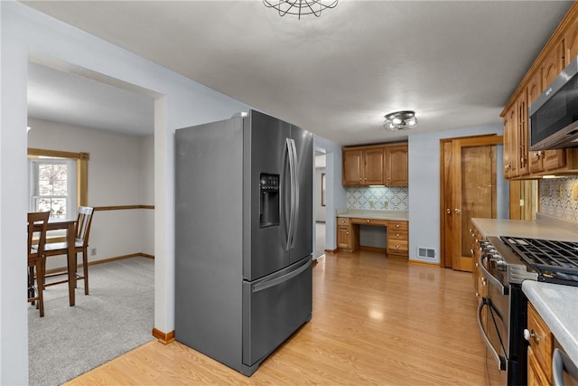 2425 Park Ave, South Franklin, PA 15301 - kitchen featuring appliances with stainless steel finishes, built in study area, light countertops, brown cabinetry, and backsplash