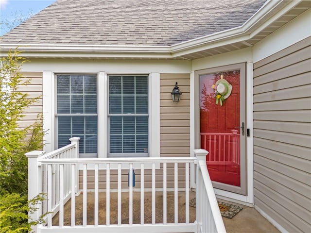 doorway to property featuring roof with shingles