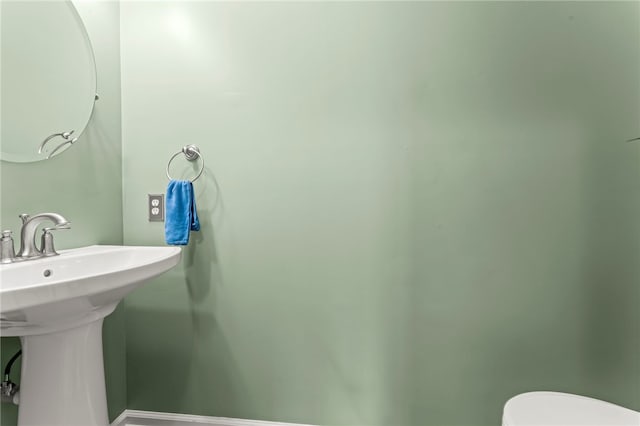half bath with baseboards and toilet