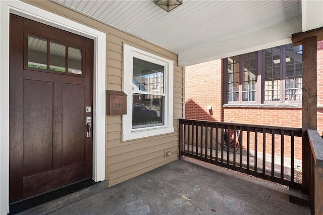 view of exterior entry with a porch and brick siding