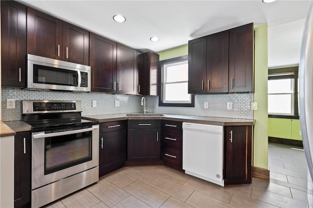 kitchen featuring dark brown cabinets, appliances with stainless steel finishes, a sink, recessed lighting, and decorative backsplash