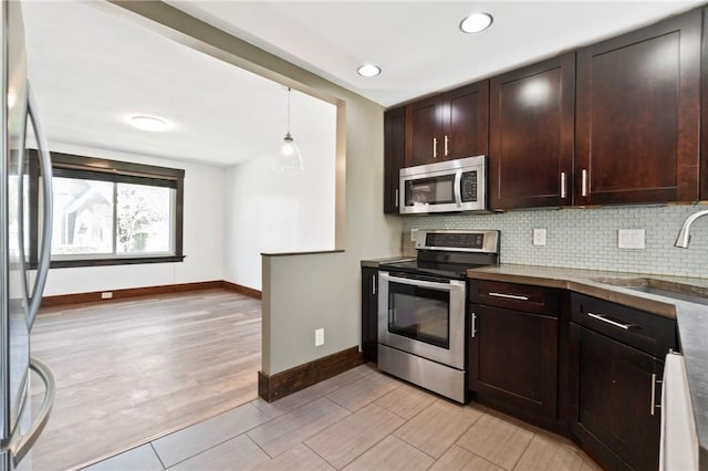 kitchen with baseboards, appliances with stainless steel finishes, a sink, and tasteful backsplash