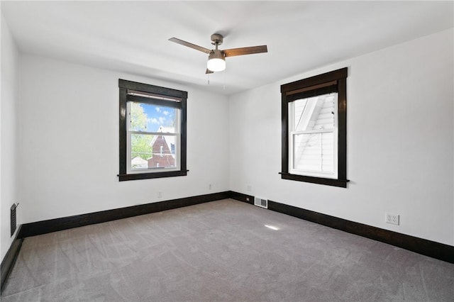 carpeted empty room with visible vents, baseboards, and ceiling fan