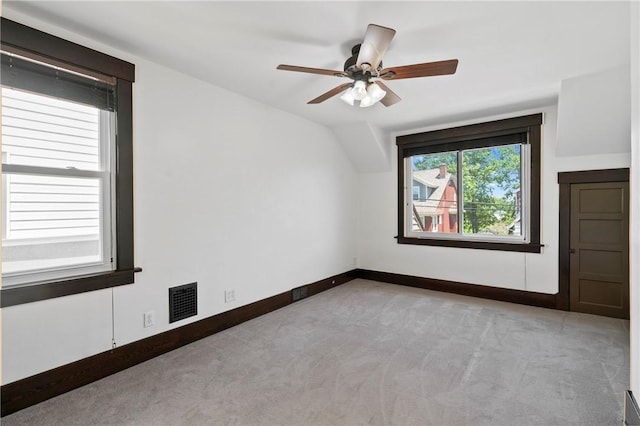 interior space with visible vents, carpet floors, baseboards, ceiling fan, and vaulted ceiling