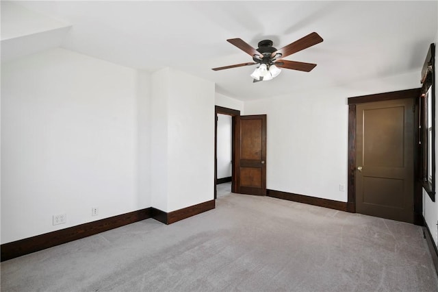 carpeted empty room featuring baseboards and a ceiling fan