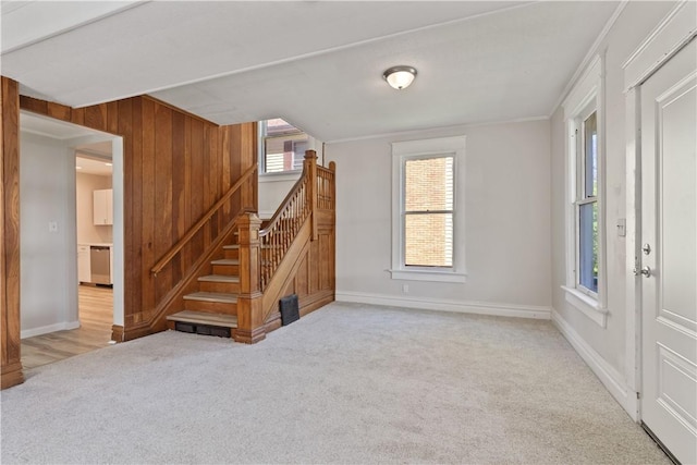 unfurnished living room featuring carpet floors, baseboards, and stairs