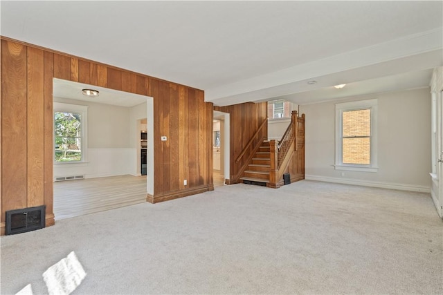 unfurnished living room featuring visible vents, light carpet, stairway, and a wealth of natural light